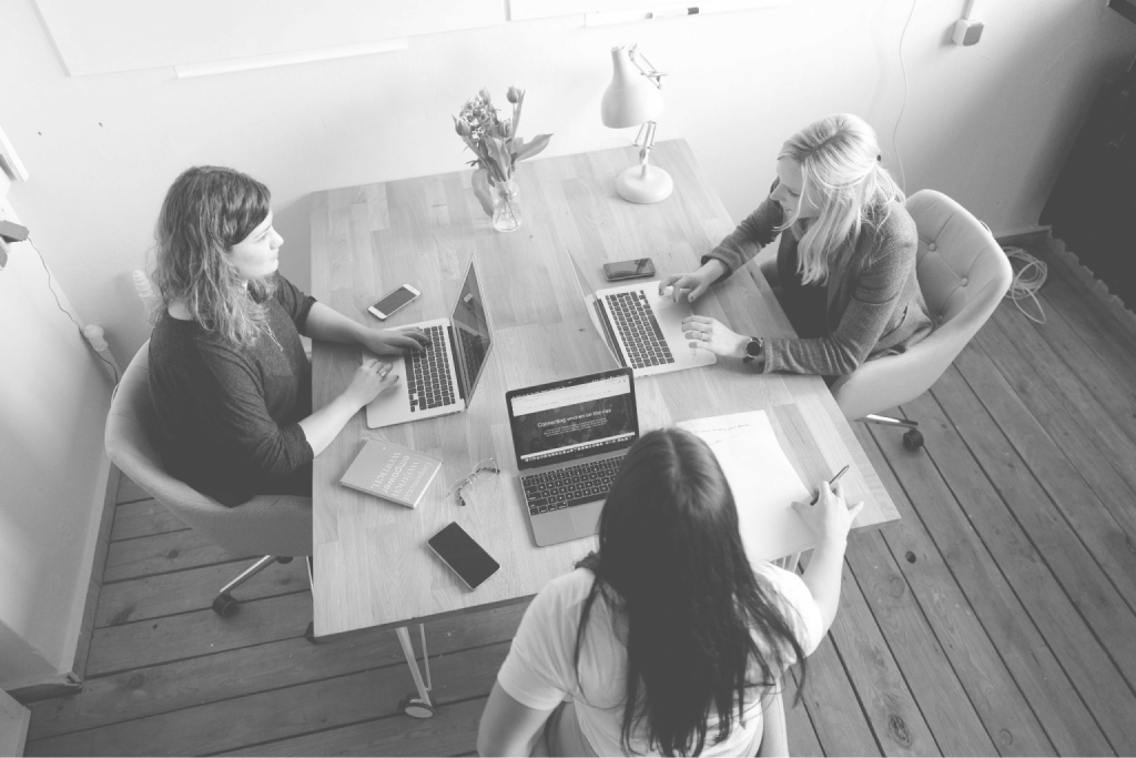 Equipo de trabajo colaborando alrededor de una mesa con laptops